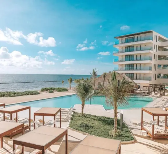 Infinity pool with ocean views, surrounded by cabanas and palm trees at Sensira Resort.