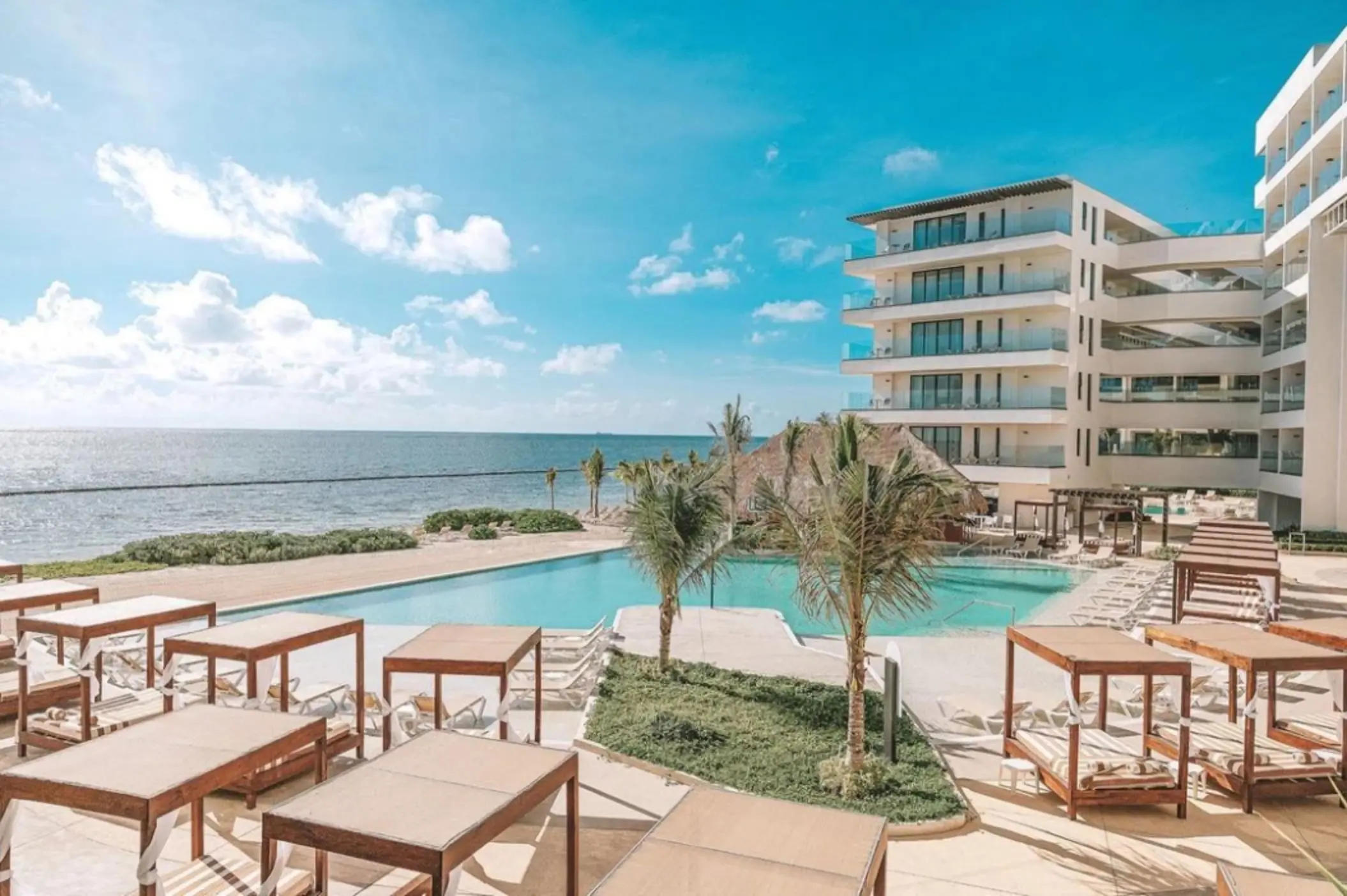 Infinity pool with ocean views, surrounded by cabanas and palm trees at Sensira Resort.