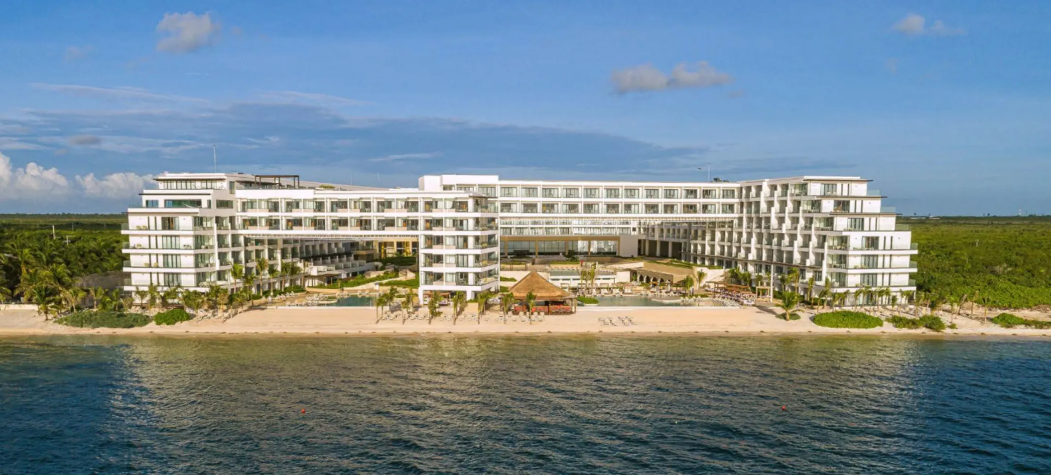 Wide beachfront resort view showing white building architecture and calm Caribbean waters.