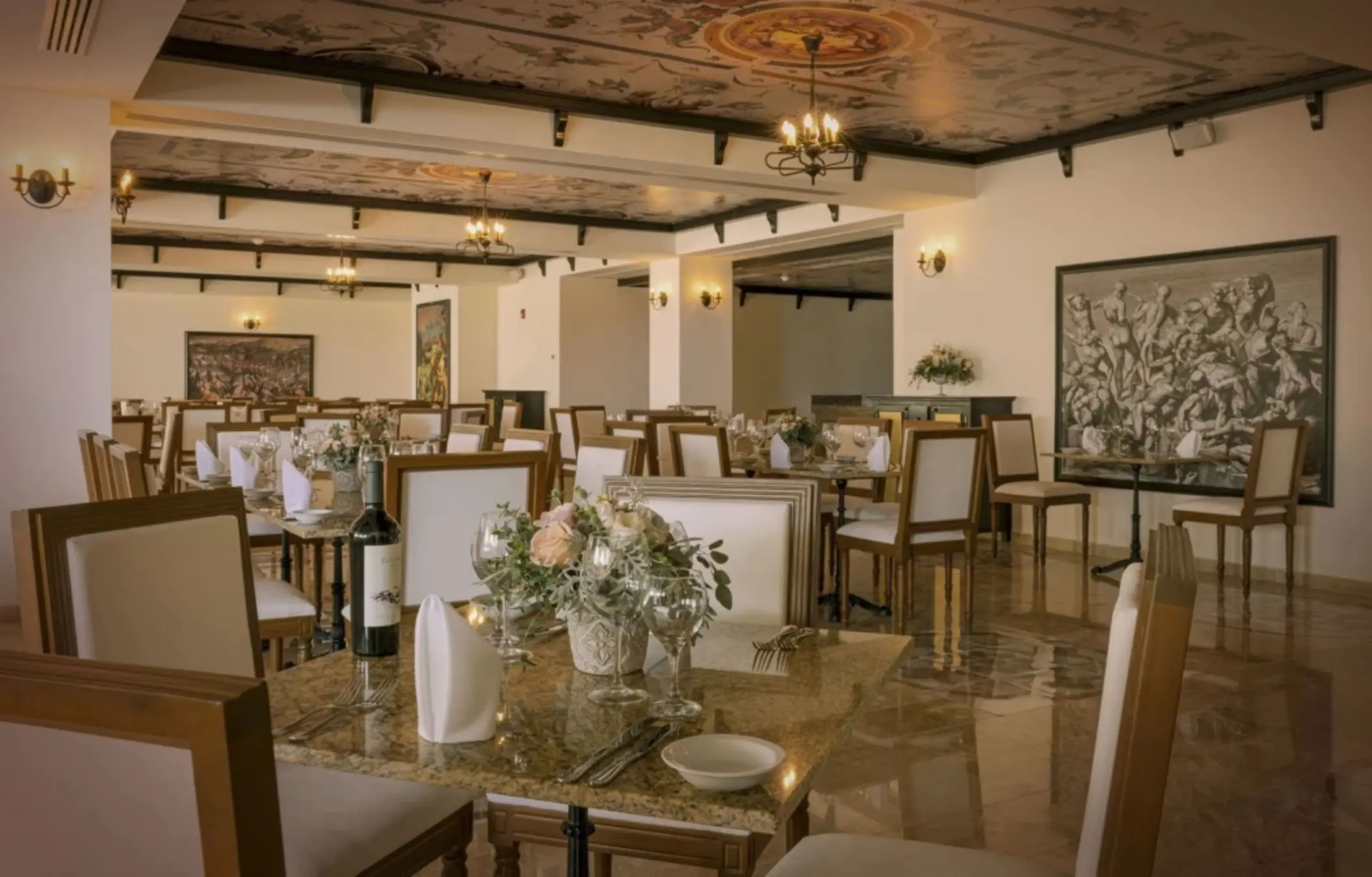 Elegant indoor restaurant with white tablecloths, floral centerpieces, and Renaissance-style artwork.