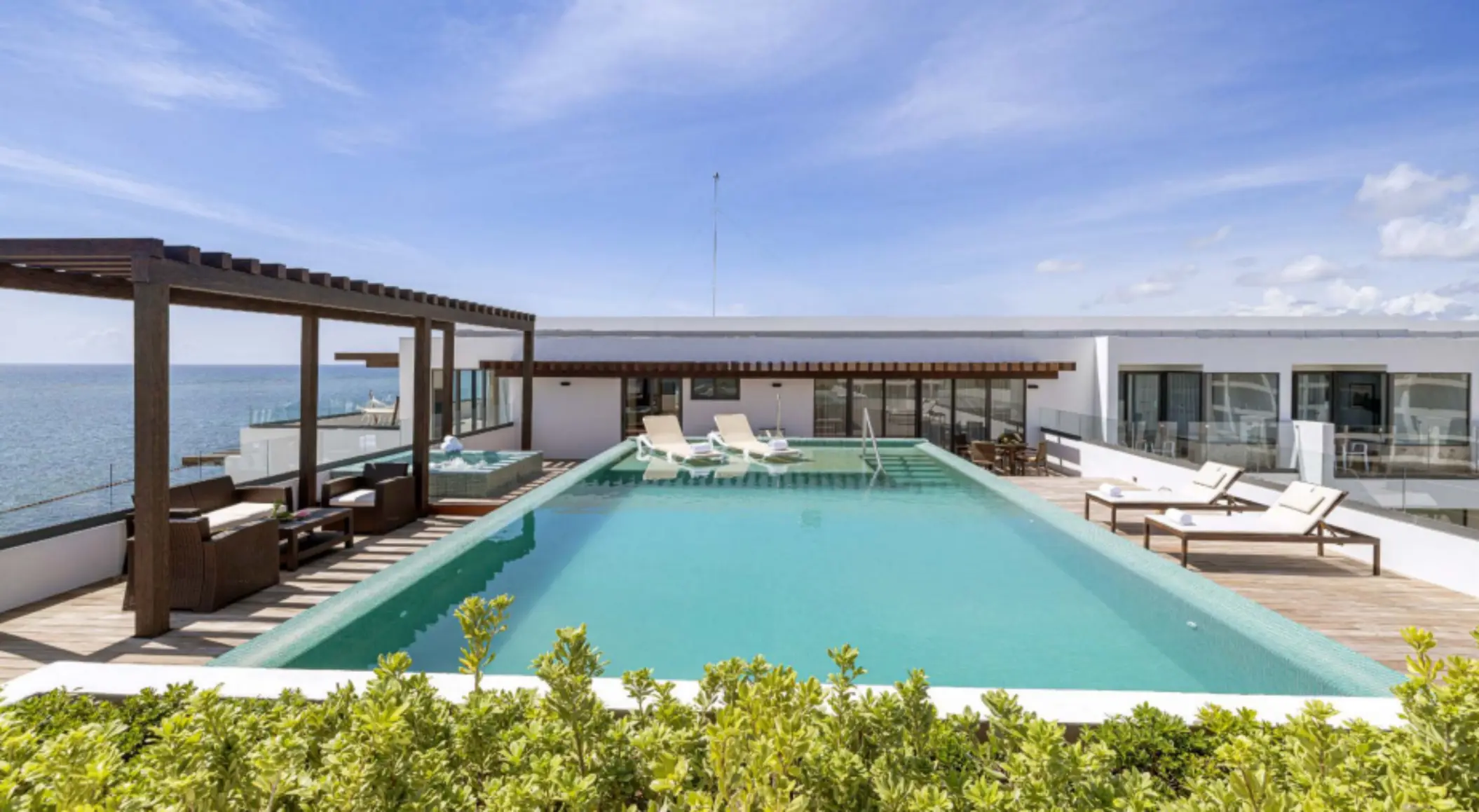 Penthouse terrace with ocean views, private infinity pool, sun loungers, and shaded outdoor seating area.