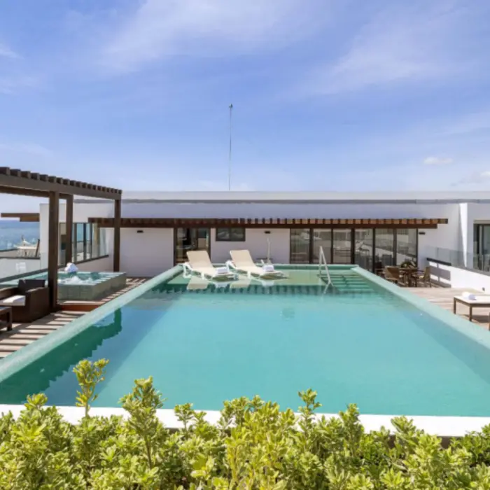 Penthouse terrace with ocean views, private infinity pool, sun loungers, and shaded outdoor seating area.