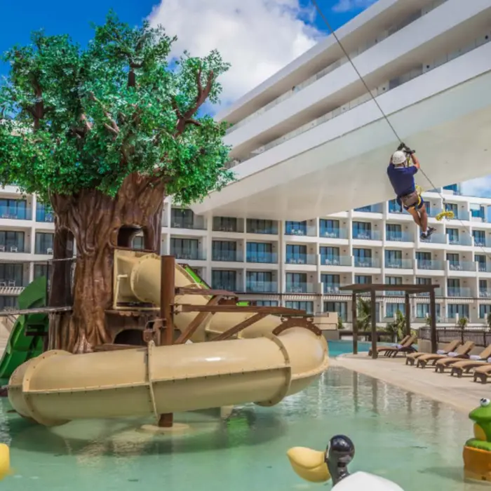Colorful kids’ water park with treehouse slides and zip line, perfect for family fun by the poolside.