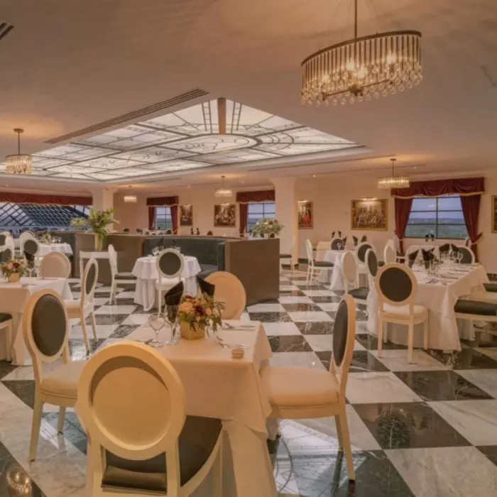 Refined dining room with black and white floors, chandeliers, and round tables set for dinner service.