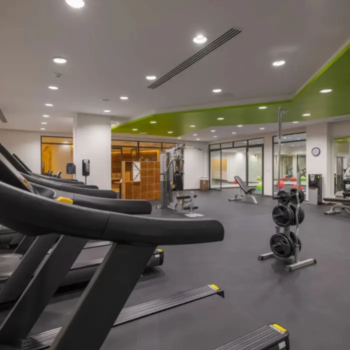 Modern gym with treadmills, weight training equipment, and green ceiling accent at Sensira Resort.