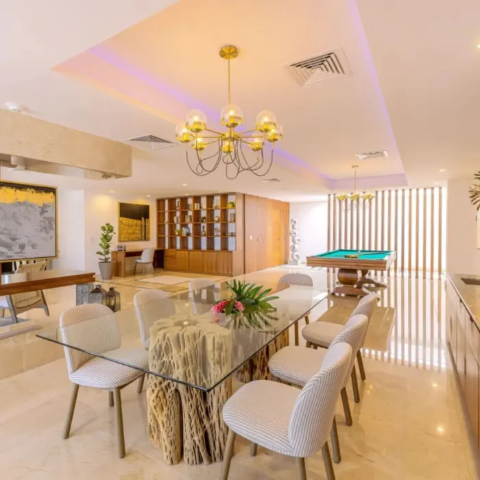 Stylish indoor lounge with glass dining table, pool table, and built-in wooden shelves and decor.