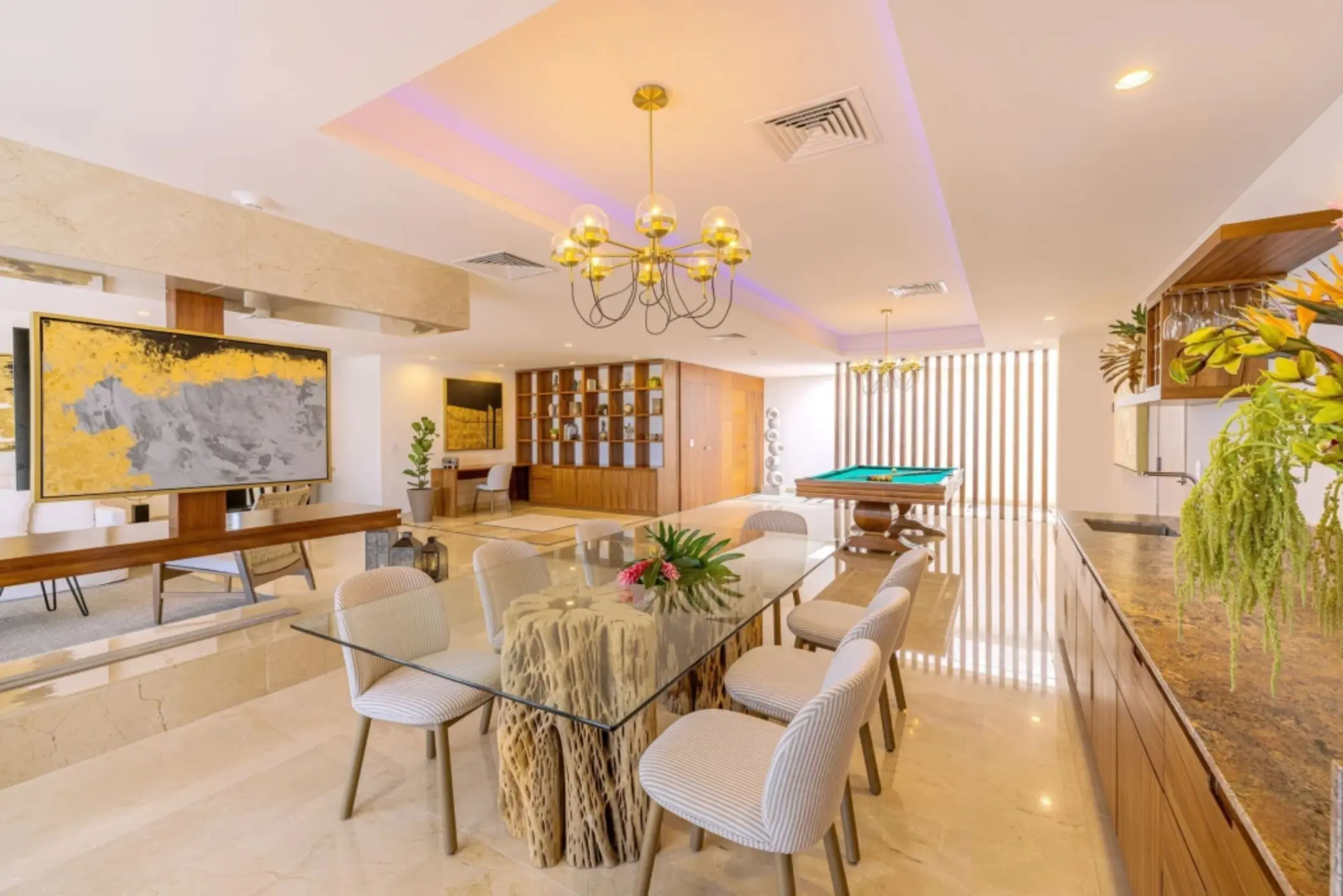 Stylish indoor lounge with glass dining table, pool table, and built-in wooden shelves and decor.