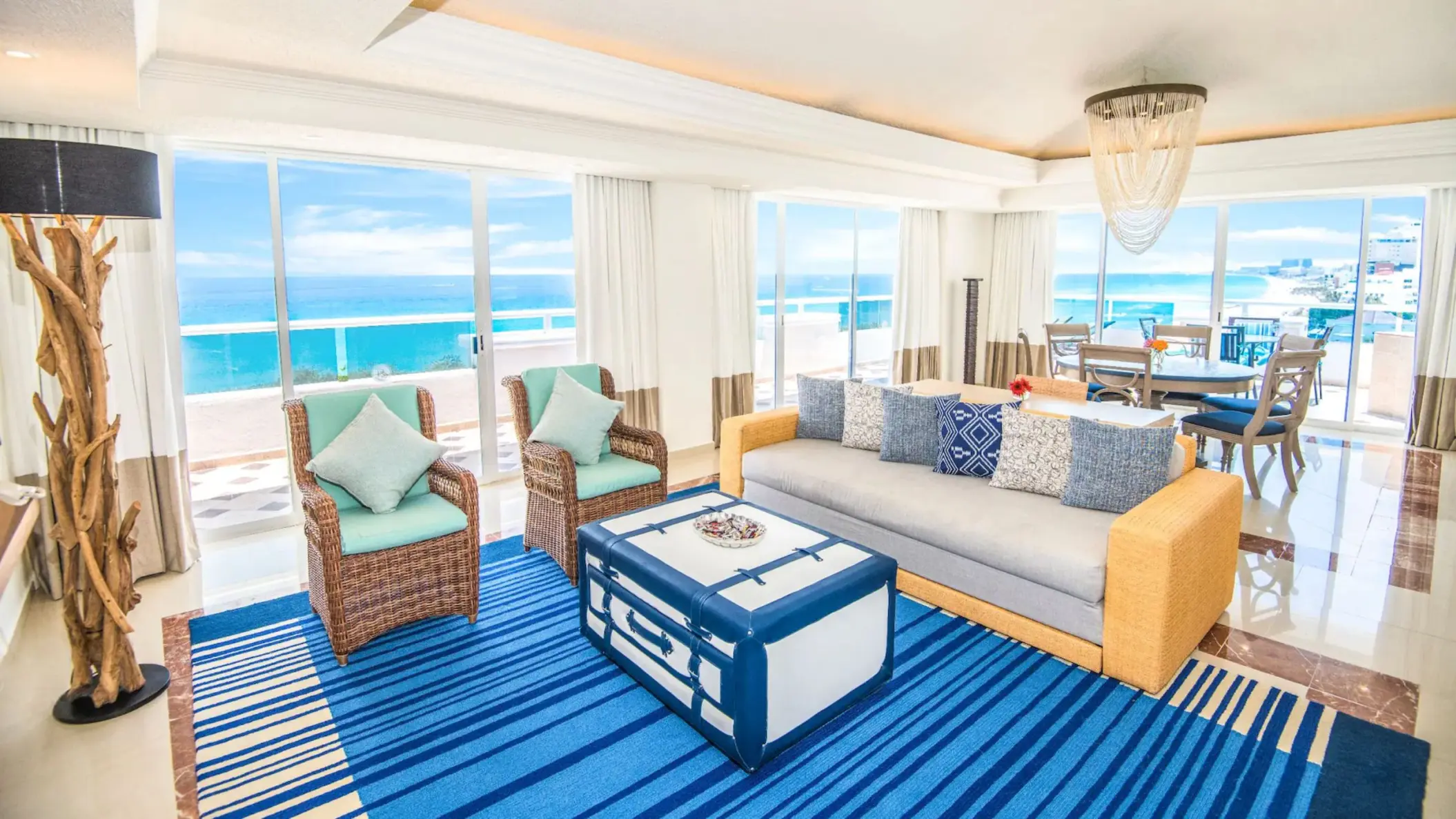 The living area of a presidential suite with a couch, chairs, and a breathtaking ocean view.
