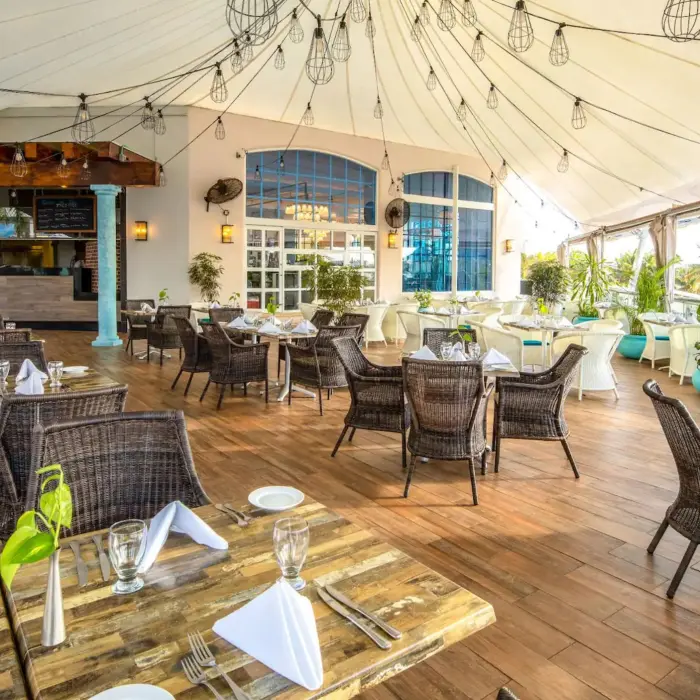 An upscale indoor restaurant with wicker chairs, string lights, and a full bar.