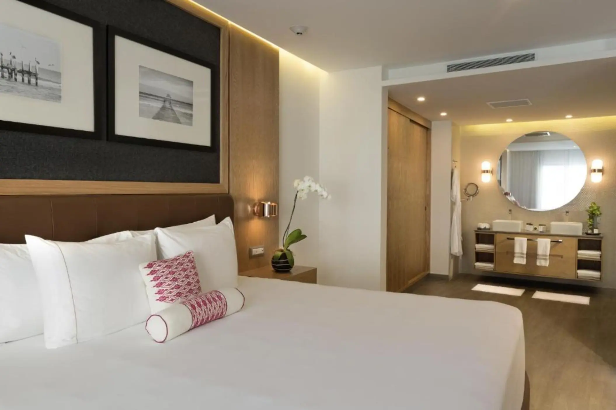A modern and elegant one-bedroom suite featuring a large bed, contemporary furnishings, and a spacious bathroom with a double vanity and large mirror.