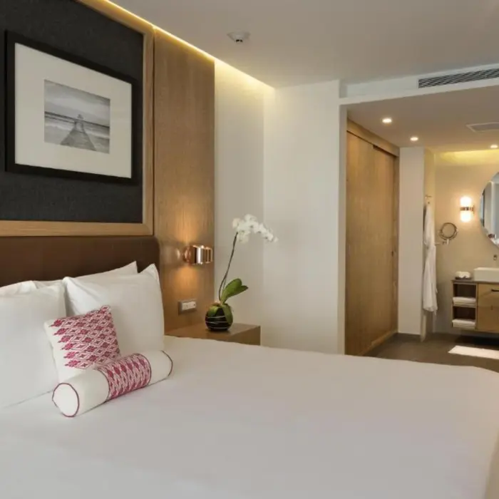 A modern and elegant one-bedroom suite featuring a large bed, contemporary furnishings, and a spacious bathroom with a double vanity and large mirror.