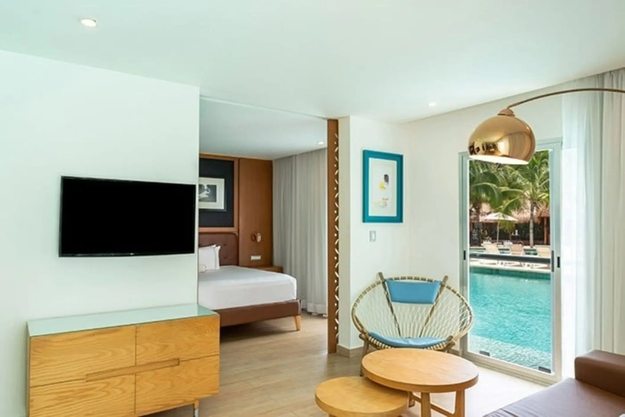 Interior of a swim-out suite, featuring a bedroom and a living area with a television, and large sliding doors opening directly to a pool.