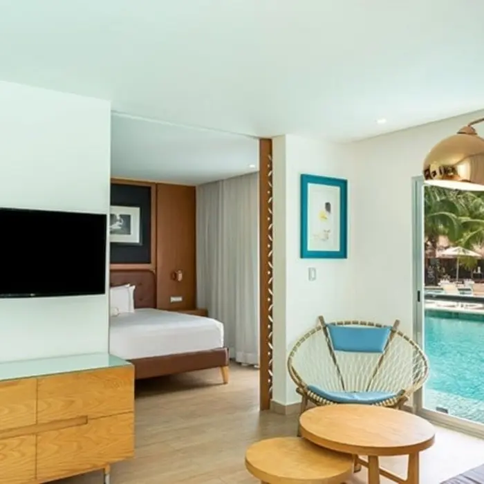 Interior of a swim-out suite, featuring a bedroom and a living area with a television, and large sliding doors opening directly to a pool.