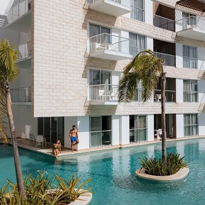 Exterior of swim-up suites at The Fives Beach Hotel, with guests enjoying direct access to a refreshing pool surrounded by palm trees and modern architecture.