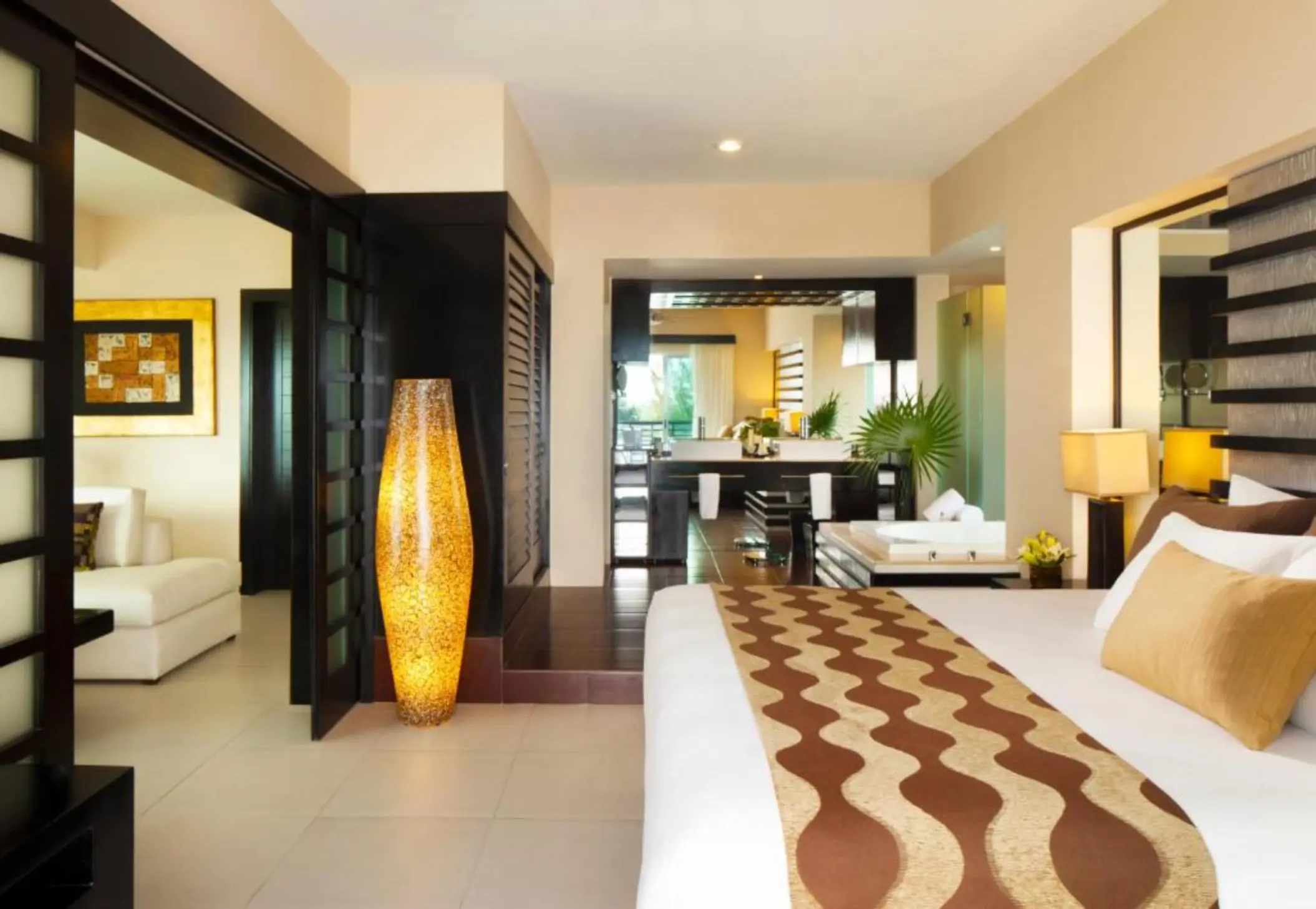 Interior of a spacious two-bedroom residence, showing a stylishly decorated bedroom with a large bed, modern furnishings, and a view into the living area.