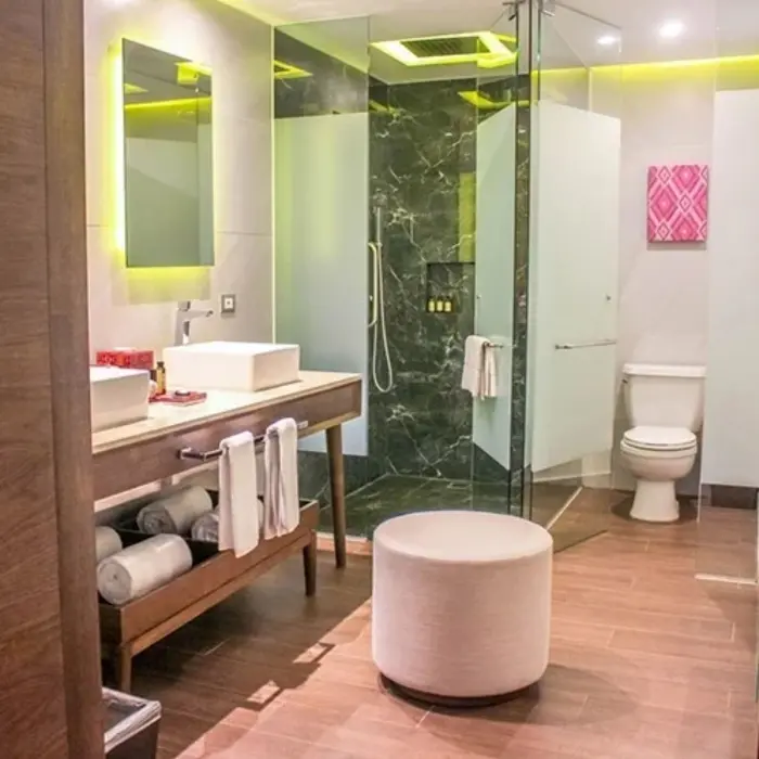 Modern bathroom with green accent lighting, marble shower, and double vanity.