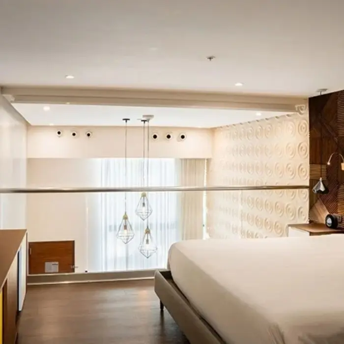 Loft-style room with king bed, wood finishes, hanging lights, and overlook view of floor-to-ceiling windows.