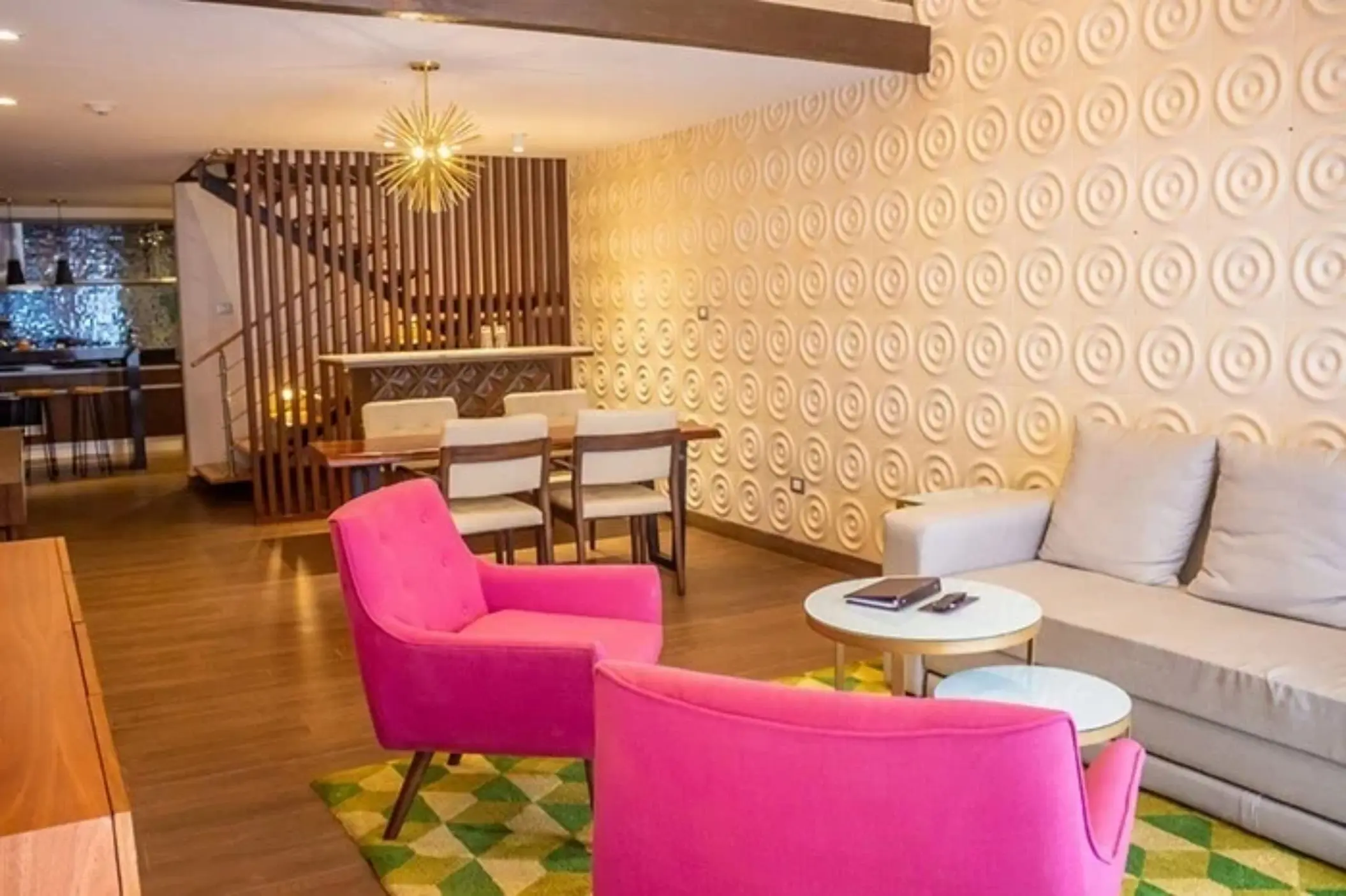 Bright suite with dining table, lounge area, and designer lighting features.