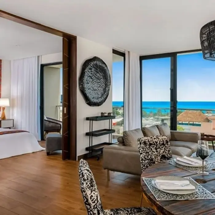 Luxury suite with ocean views, modern dining area, open-concept design, and separate bedroom with king bed.