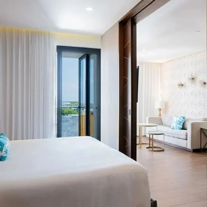Spacious suite with king bed, sliding doors, and separate living room with balcony and natural light.