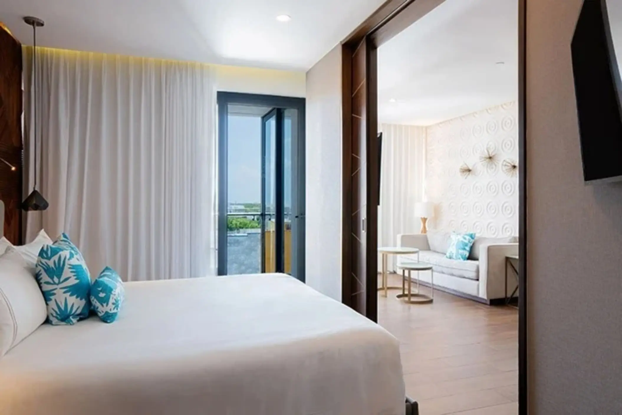 Spacious suite with king bed, sliding doors, and separate living room with balcony and natural light.