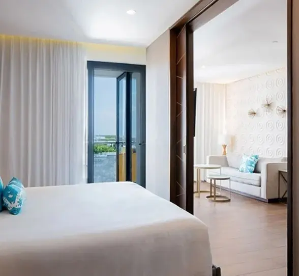 Spacious suite with king bed, sliding doors, and separate living room with balcony and natural light.