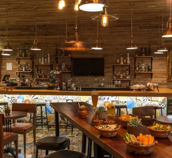 Rustic-themed indoor bar with wooden decor, vintage portraits, and artisanal cocktails.