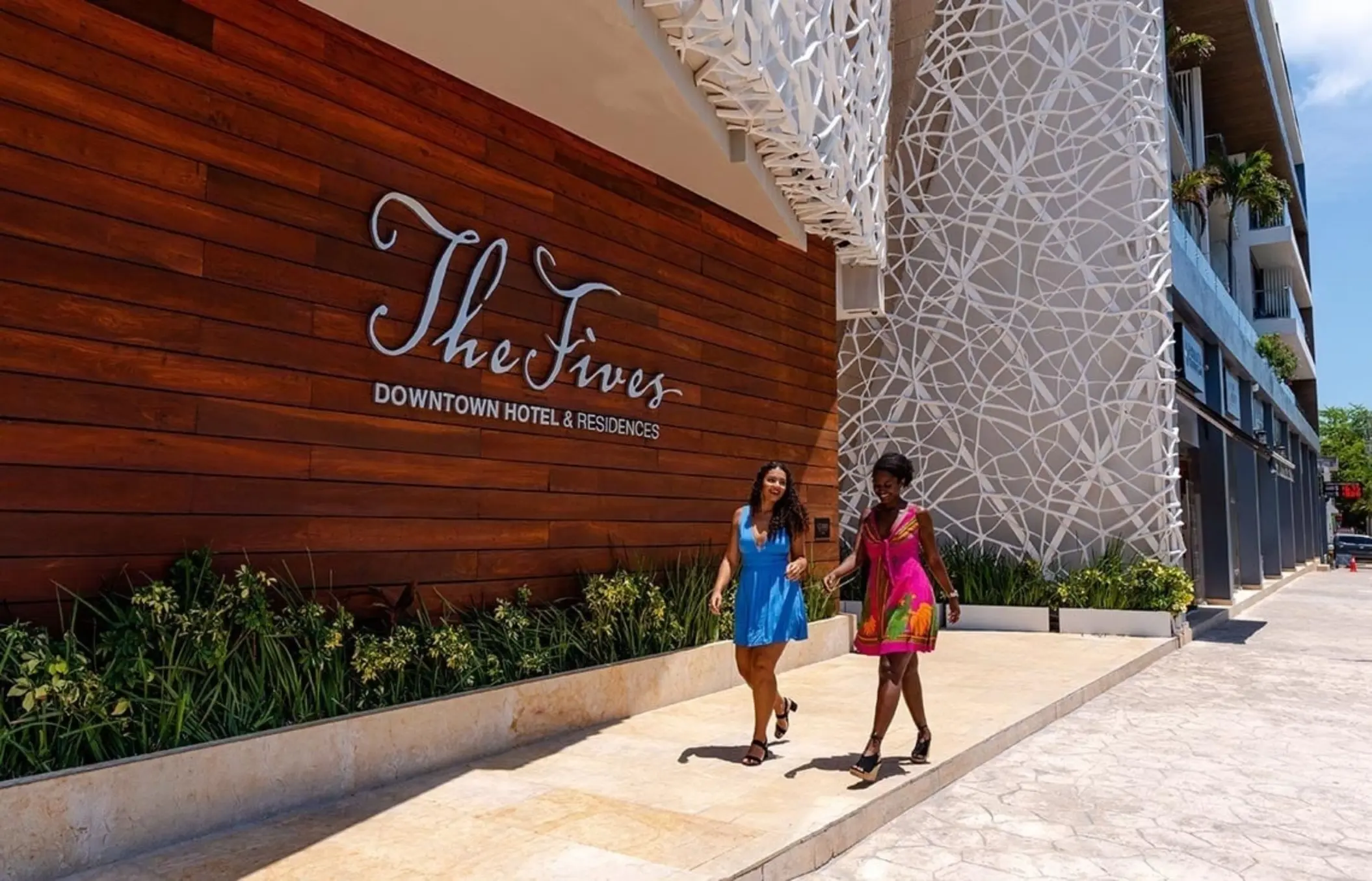 Exterior view of The Fives Downtown Hotel & Residences with wood facade & logo signage.