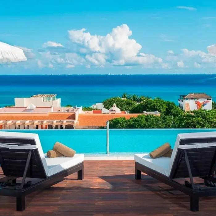 Rooftop infinity pool with ocean views and modern lounge chairs in Playa del Carmen.