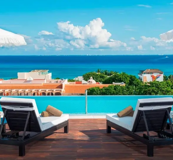 Rooftop infinity pool with ocean views and modern lounge chairs in Playa del Carmen.