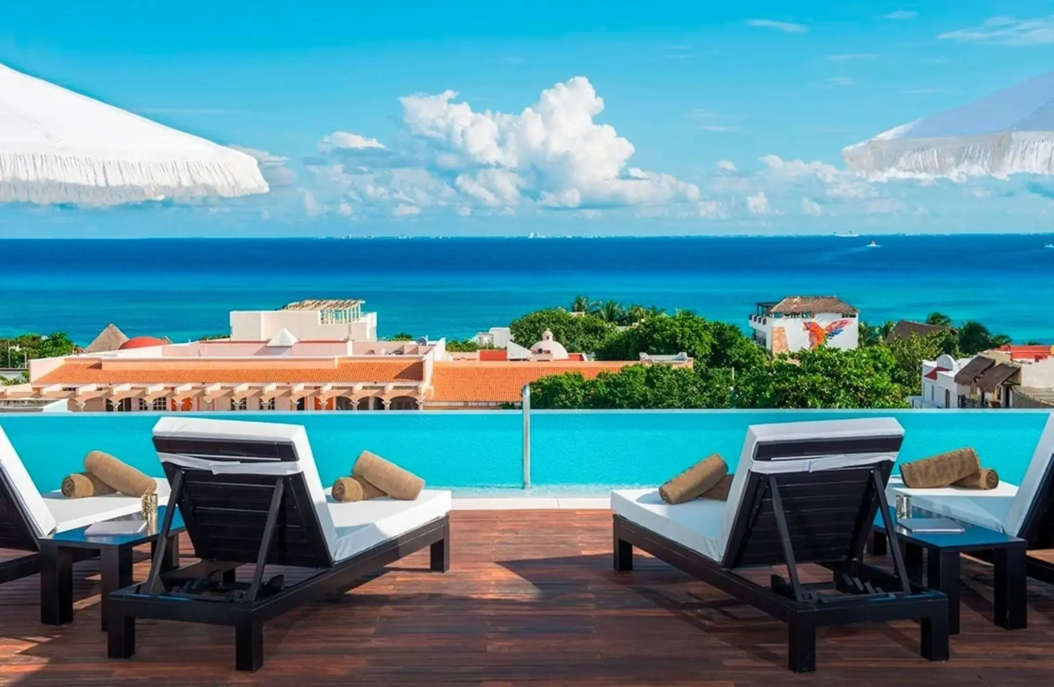 Rooftop infinity pool with ocean views and modern lounge chairs in Playa del Carmen.