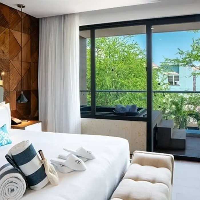 Stylish guest room with wood accent wall, balcony view, and plush white bedding.