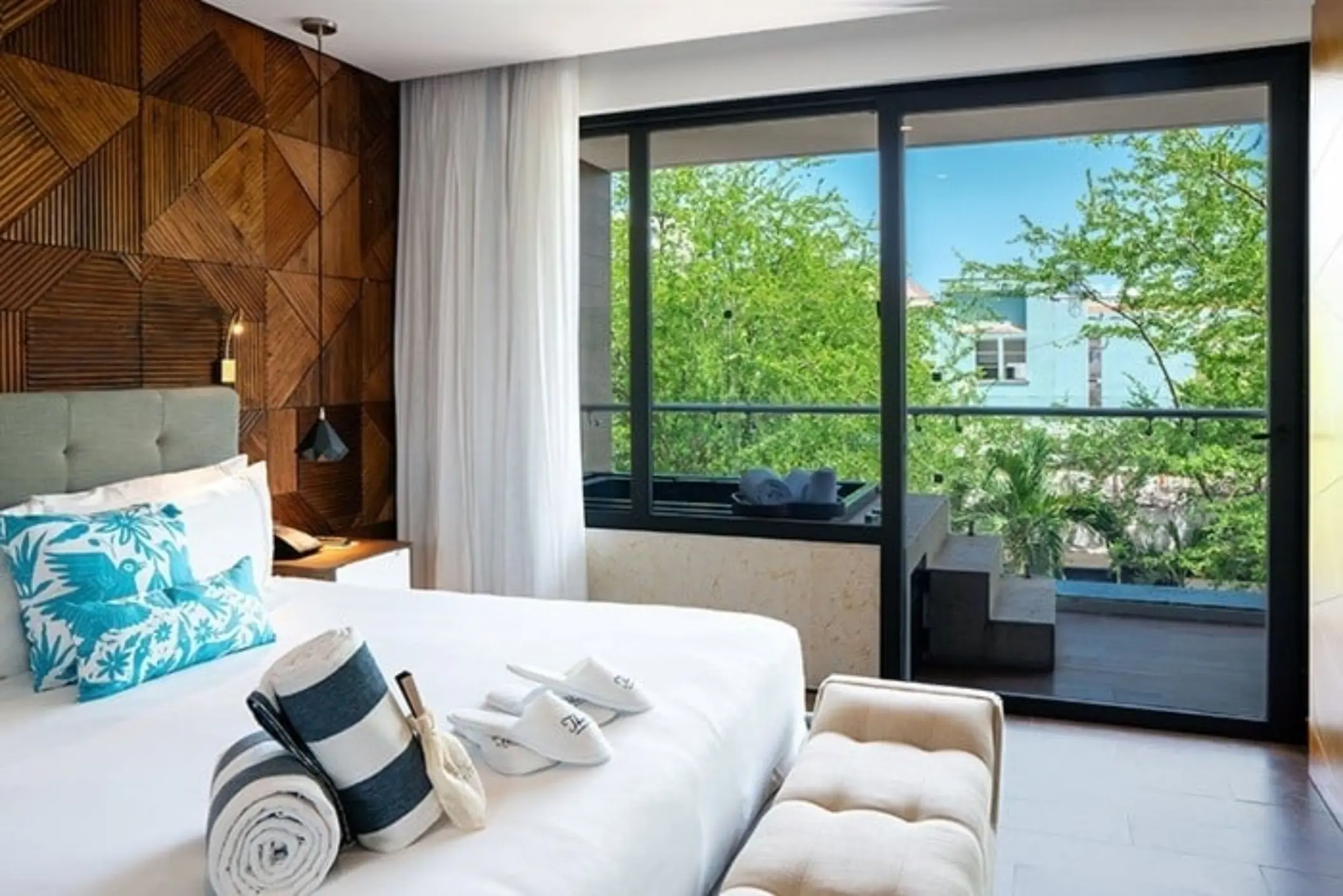 Stylish guest room with wood accent wall, balcony view, and plush white bedding.