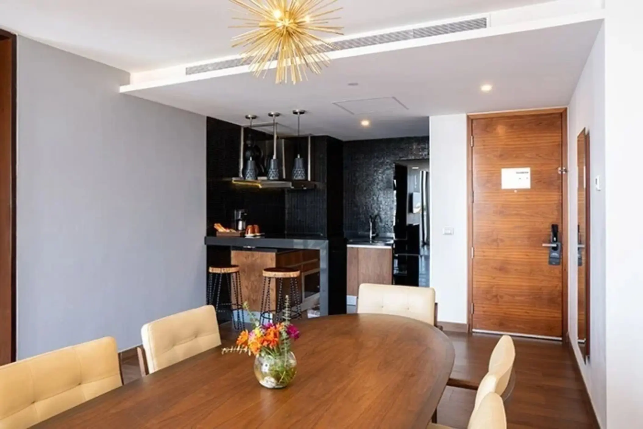 Upscale suite dining area with floral centerpiece, kitchen bar, and modern lighting.