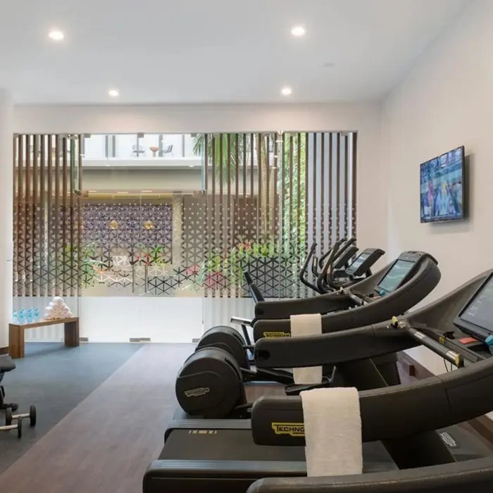Resort fitness center with Technogym equipment, flat-screen TVs, and natural light.