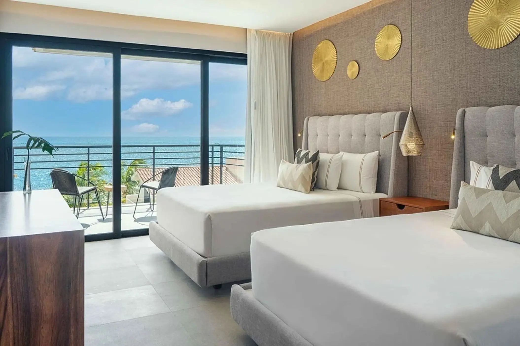 Oceanview double room with balcony seating, tufted headboards, and golden wall accents.