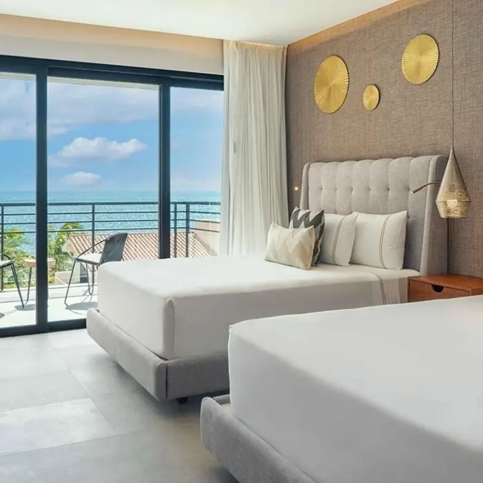 Oceanview double room with balcony seating, tufted headboards, and golden wall accents.