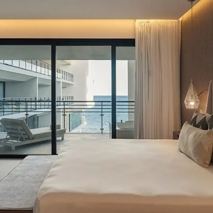 Spacious king bedroom with a private balcony and partial ocean view, featuring elegant decor and soft lighting.