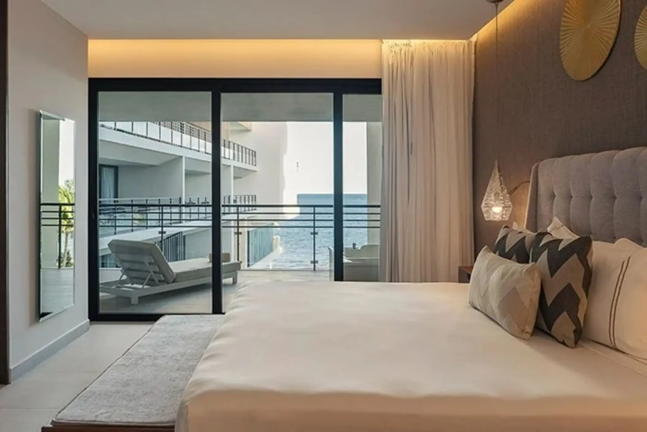 Spacious king bedroom with a private balcony and partial ocean view, featuring elegant decor and soft lighting.