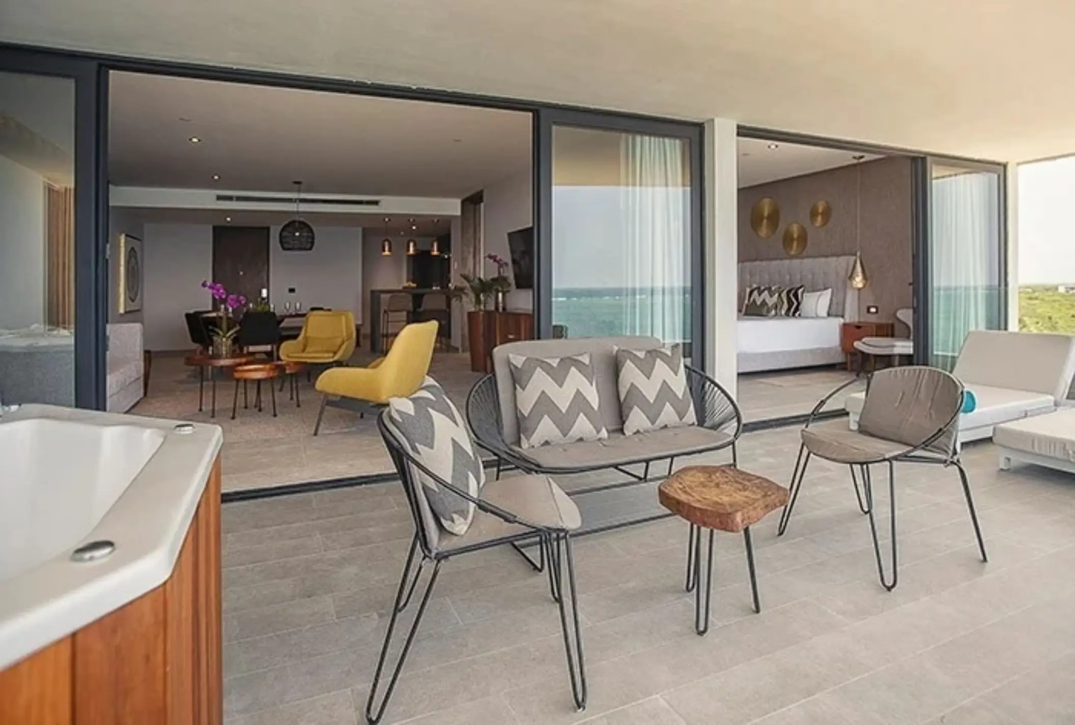 Spacious balcony with seating, outdoor jacuzzi, and direct access to the interior suite with ocean views.