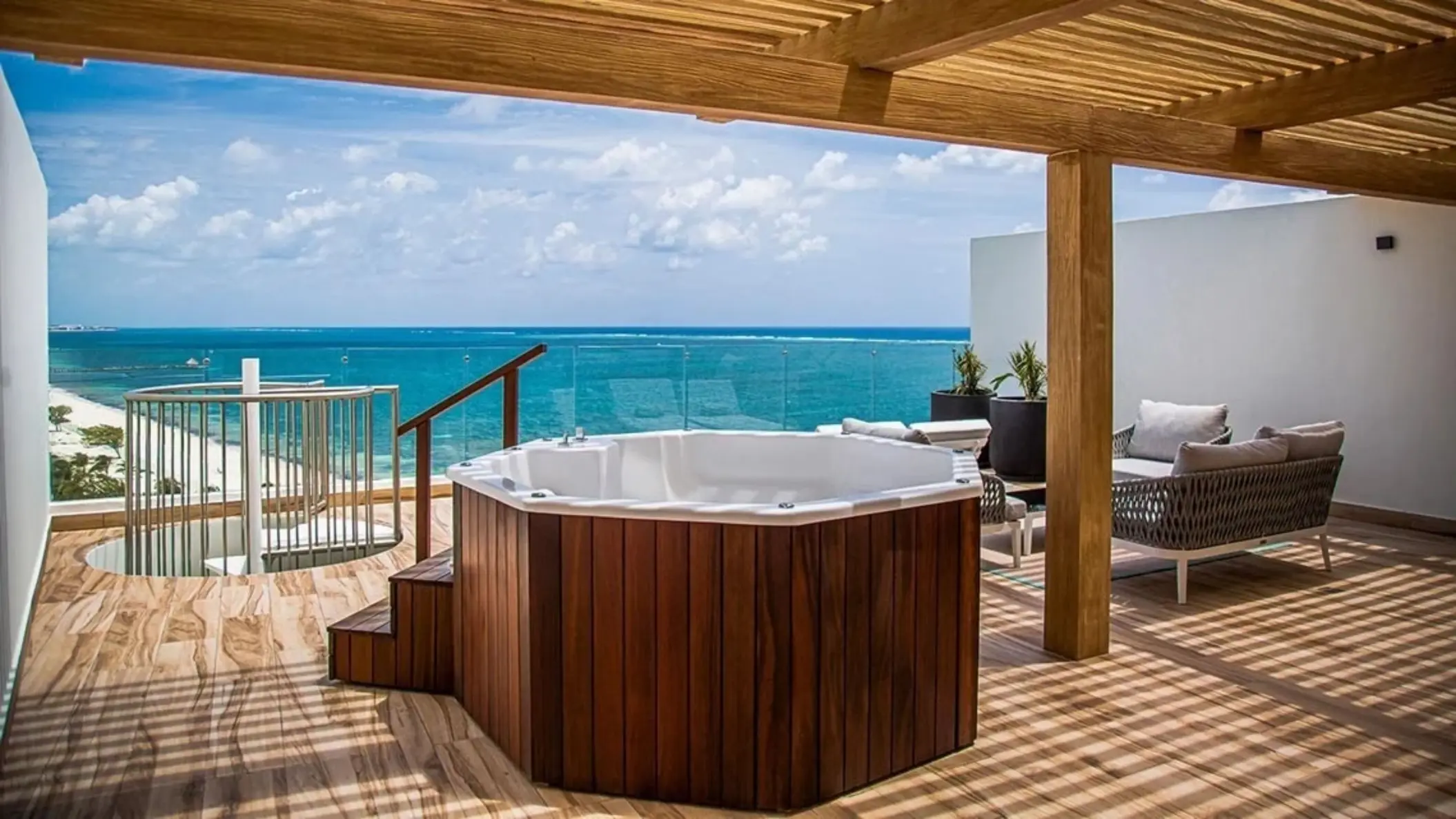 Rooftop terrace with wooden pergola, private jacuzzi, and ocean views, featuring modern outdoor furniture.