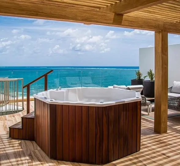 Rooftop terrace with wooden pergola, private jacuzzi, and ocean views, featuring modern outdoor furniture.