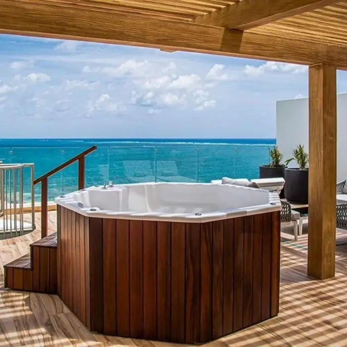 Rooftop terrace with wooden pergola, private jacuzzi, and ocean views, featuring modern outdoor furniture.