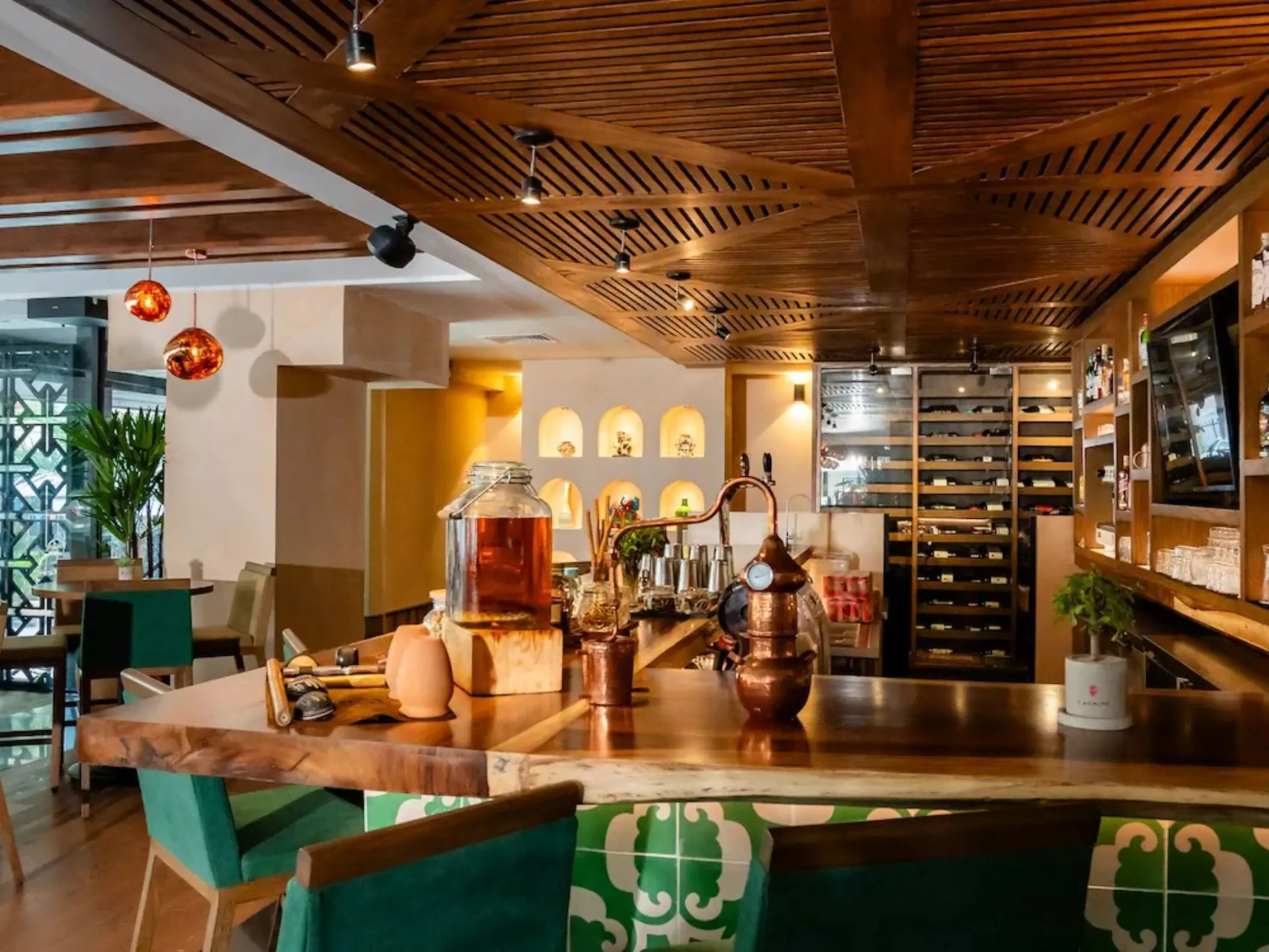 The inviting Bar Capricho at The Reef 28, with a rustic wooden counter, various bottles, and decorative lighting.