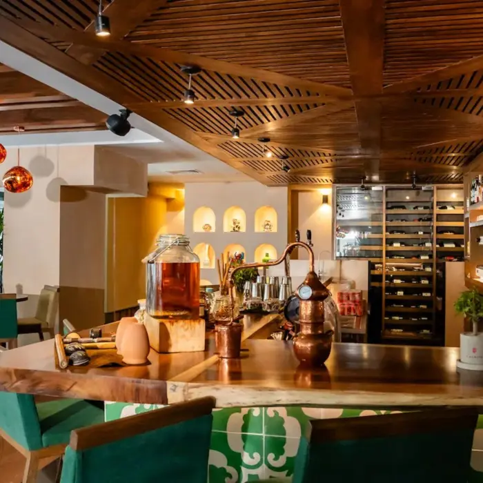The inviting Bar Capricho at The Reef 28, with a rustic wooden counter, various bottles, and decorative lighting.