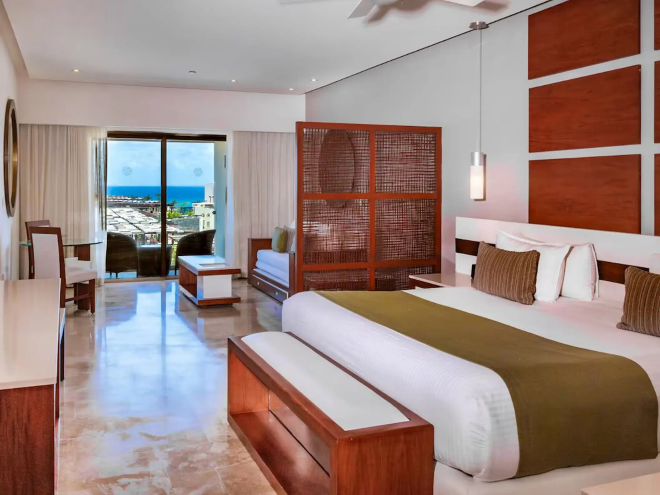 A well-appointed junior suite at The Reef 28 with a king-size bed and a balcony offering partial ocean views.