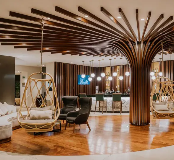The stylish reception and lobby bar at The Reef 28, featuring unique tree-like wooden columns and hanging chairs.