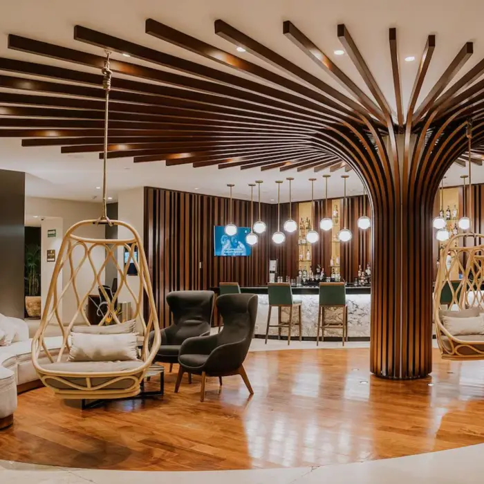 The stylish reception and lobby bar at The Reef 28, featuring unique tree-like wooden columns and hanging chairs.