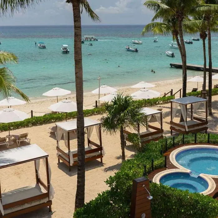 Aerial view of the hotel's hot tubs and beach with palm trees and sun umbrellas.