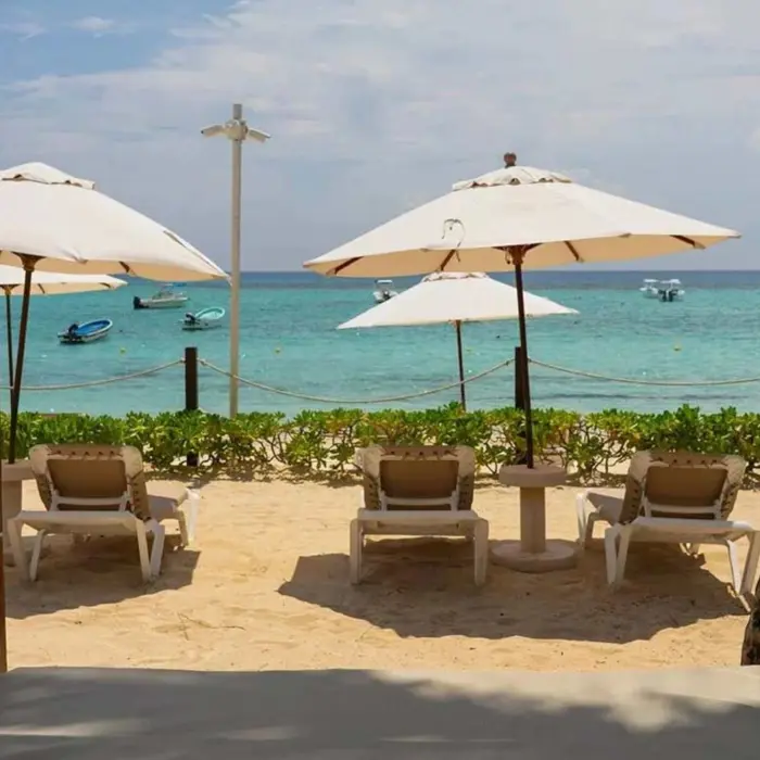 Beachfront setup with sun loungers, parasols, and cabanas overlooking the turquoise ocean.